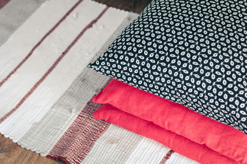 Cozy home interior decor, decorative pillows in front of white nightstand near a multi-colored rug background.