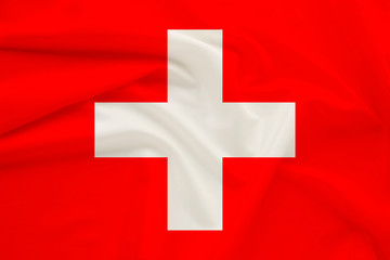 Obraz premium national flag of switzerland on delicate silk with wind folds, travel concept, immigration, politics