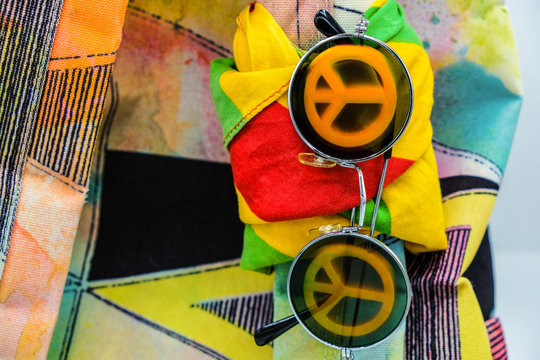 Vintage sunglasses with the symbol of pacifist movement and colored scarves are fixed on a backpack.