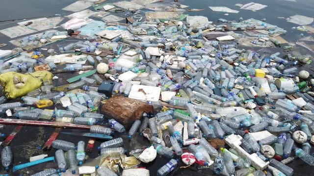 Plastic pollution trash in ocean with different kinds of garbage - plastic bottles, bags, wastes floating in water. Sea ocean water pollution concept. Plastic pollution crisis