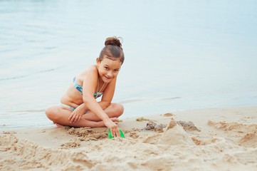 Adorable little girl building a sandcastlle at the seashore