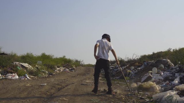 Boy rummaging in garbage with stick