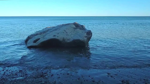 Olas peque&ntilde;as golpean roca en la orilla de la playa en una tarde de verano en Las Grutas