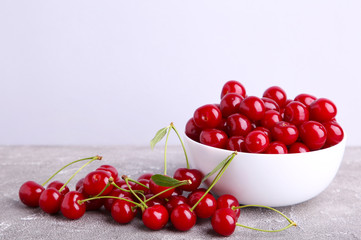 Fresh red cherry fruit in bowl on grey concrete background