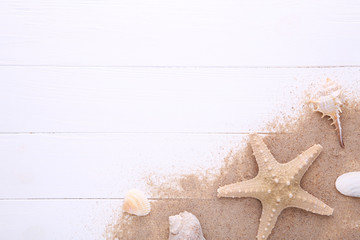 Fototapeta na wymiar Starfish and seashells with sand on a white wooden background with copy space. Summer concept