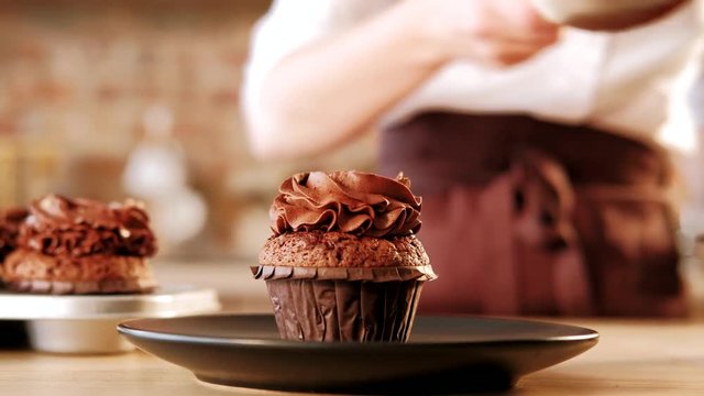 Patisserie culinary courses. Chef putting chocolate cupcake on a plate.
