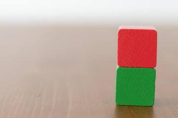 Stacked red and green wooden cube on wooden table with copyspace beside