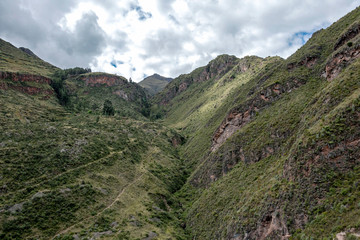 Naklejka na ściany i meble Landscape with green Andean Mountains and Inca ruins on the hiking path in Pisac archeological park, Peru