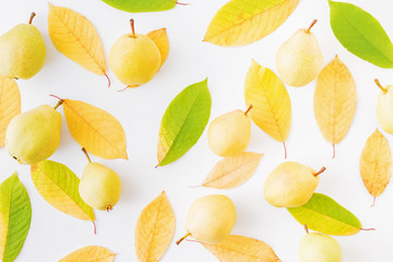 Flat lay pattern with colorful autumn leaves and yellow pears on a white background