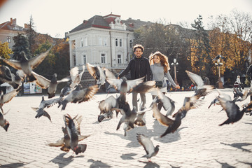 Obraz premium Cute couple in a spring city. Lady with long hair. Man in a black jacket. Two people with a dog