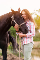 young woman standing outdoors with her black horse