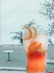 Glass of red coctail with ice, lemon, orange