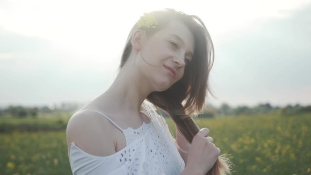 Portrait attractive young woman stand in field touch hair smile flower feel freedom blooming yellow field happy meadow green landscape sunlight model close up slow motion