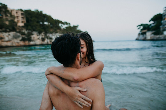 man and woman embracing near body of water