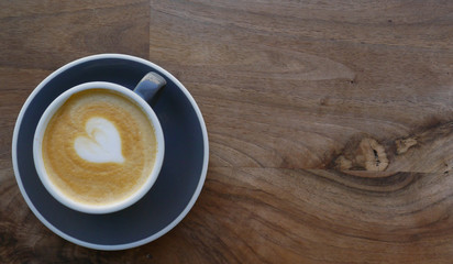 Macro photo cup of coffe cappucino in a yellow cup. Painted heart on skin coffe