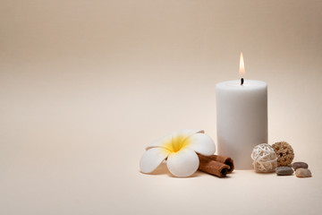 Beautiful spa composition with candle, frangipani flower and other decor elements.