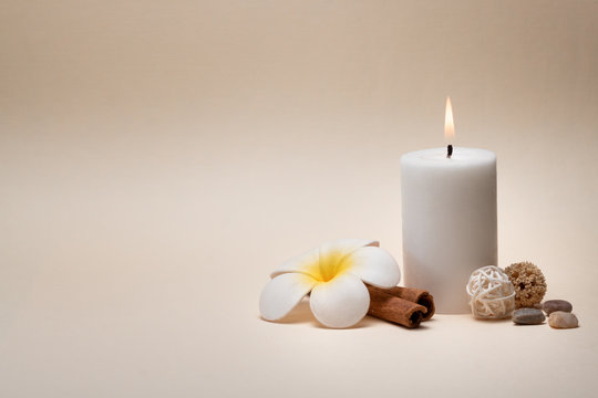 Beautiful spa composition with candle, frangipani flower and other decor elements.