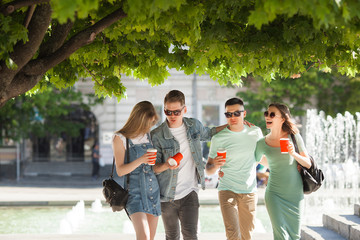 Obraz premium Young people walking around the city. Stylish friends together having fun. Group of people drinking coffee and talking.