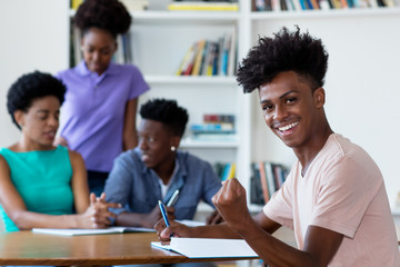 Successful african american male student learning at desk at school