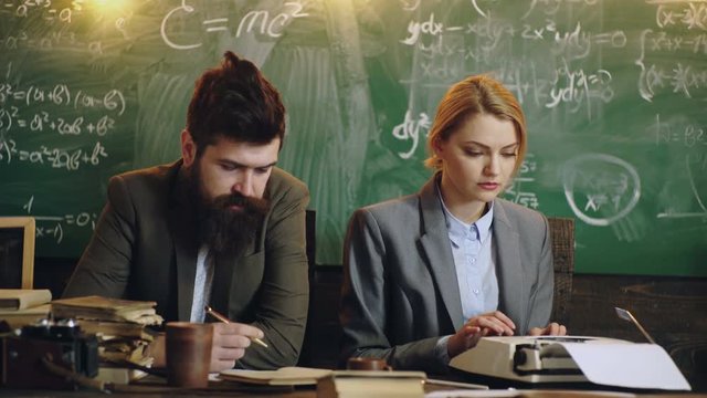 Discipline concept. Man with beard hold pen and sexy girl teacher prints on a typewriter , chalkboard on background. Lady teacher and strict schoolmaster care about discipline and rules in school.