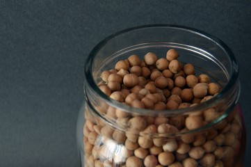 Dried chickpeas in glass jar on gray background