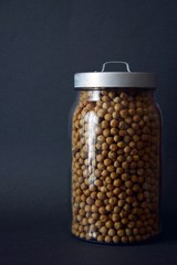 Dried chickpeas in glass jar on gray background