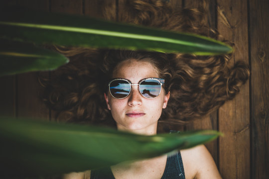 woman lying on brown wooden parquet wearing sunglasses