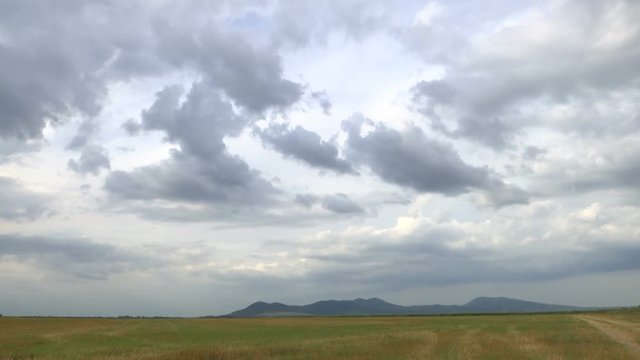 TIME LAPSE - dramatic clouds above the plain with hills in the background