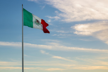 COZUMEL, MEXICO: mexican flag waving in sunset sky in Cozumel.