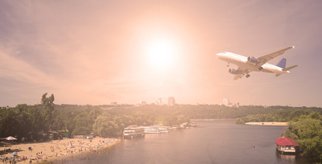 Fototapeta na wymiar Airliner over the river and the city. The evening sunset.