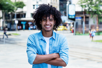 Laughing mexican young adult man with long curly hair