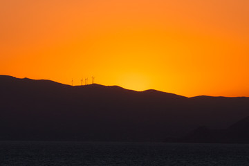 Saronic Gulf islands silhouette with wind turbines at sunset
