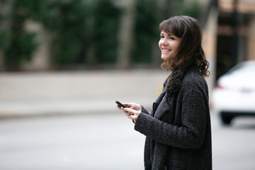 Young female using mobile phone app and waiting for a rideshare or pedestrian tourist checking...