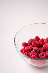 Raspberry red berries in transparent glass bowl plate tasty sweet bright on white background copy space macro