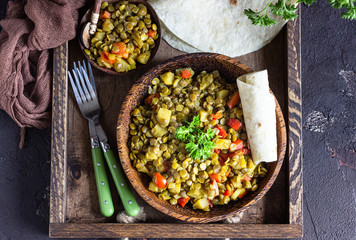 Green lentil stew (curry) with apple, bell pepper and onion. Selective focus. Dark stone background, rustic style.