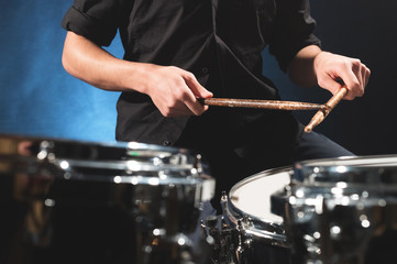 Close-up of a male drummer's hand holding drum sticks while sitting behind a drum set