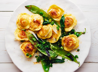 Homemade fried ravioli with parmesan and gorgonzola with green peas top view