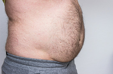 Obraz premium Big male belly, obesity and sedentary lifestyle, unhealthy diet. Isolated on white background.