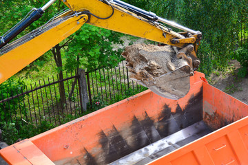 Heavy machinery working on construction site - excavator loading dump trucks during roadworks at highway. Heavy duty machinery working on construction site.