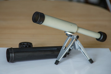 Spyglass on a small tabletop stand. Black plastic case with open lid. Selective focus close up