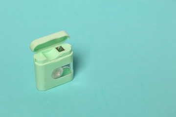 Floss container. Against the background of mint color. View from above.