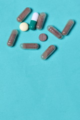 Gelatin pills and tablets of different colors. Medicines scattered on the background of mint color.