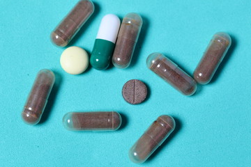 Gelatin pills and tablets of different colors. Medicines scattered on the background of mint color.