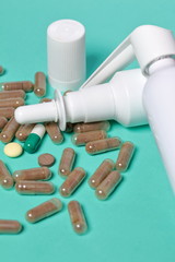 Gelatin pills and tablets of different colors. Sprays of oral and nasal sprays. Medicines scattered on the background of coral color.