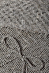 Fototapeta na wymiar Coarse linen fabric. On it lies a bow of linen thread.