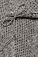 Coarse linen fabric. On it lies a bow of linen thread.