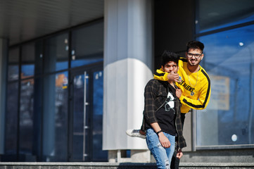 Two asian guys posed against new modern building.