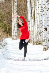Yoga in the snow. Girl practicing yoga in the Park. Time of year winter. Snow-covered trees.