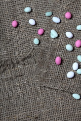 Multicolored pebbles lie on a rough linen fabric.