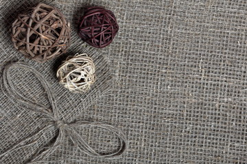 Coarse linen fabric. On it are rattan balls and a bow of linen threads.